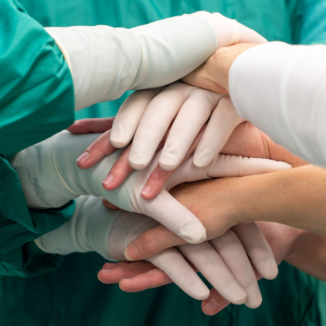 8 hands stacked on top of each other - some wearing medical gloves